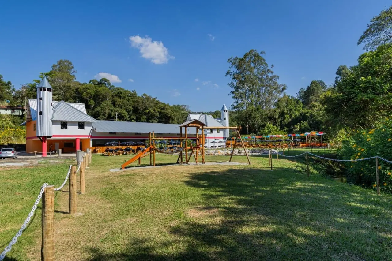 Gramado amplo do rancho com playground de madeira ao fundo