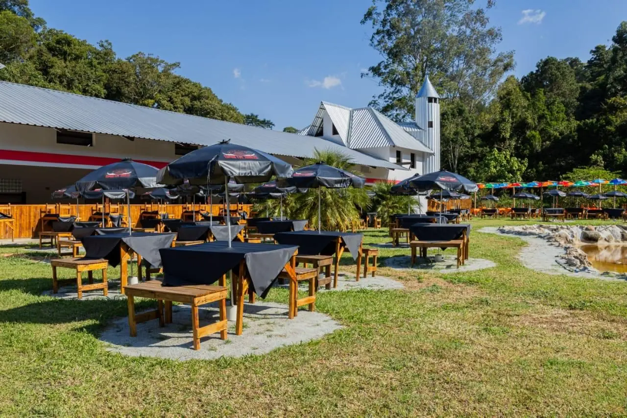 Mesas de madeira montadas no gramado do rancho para receber convidados