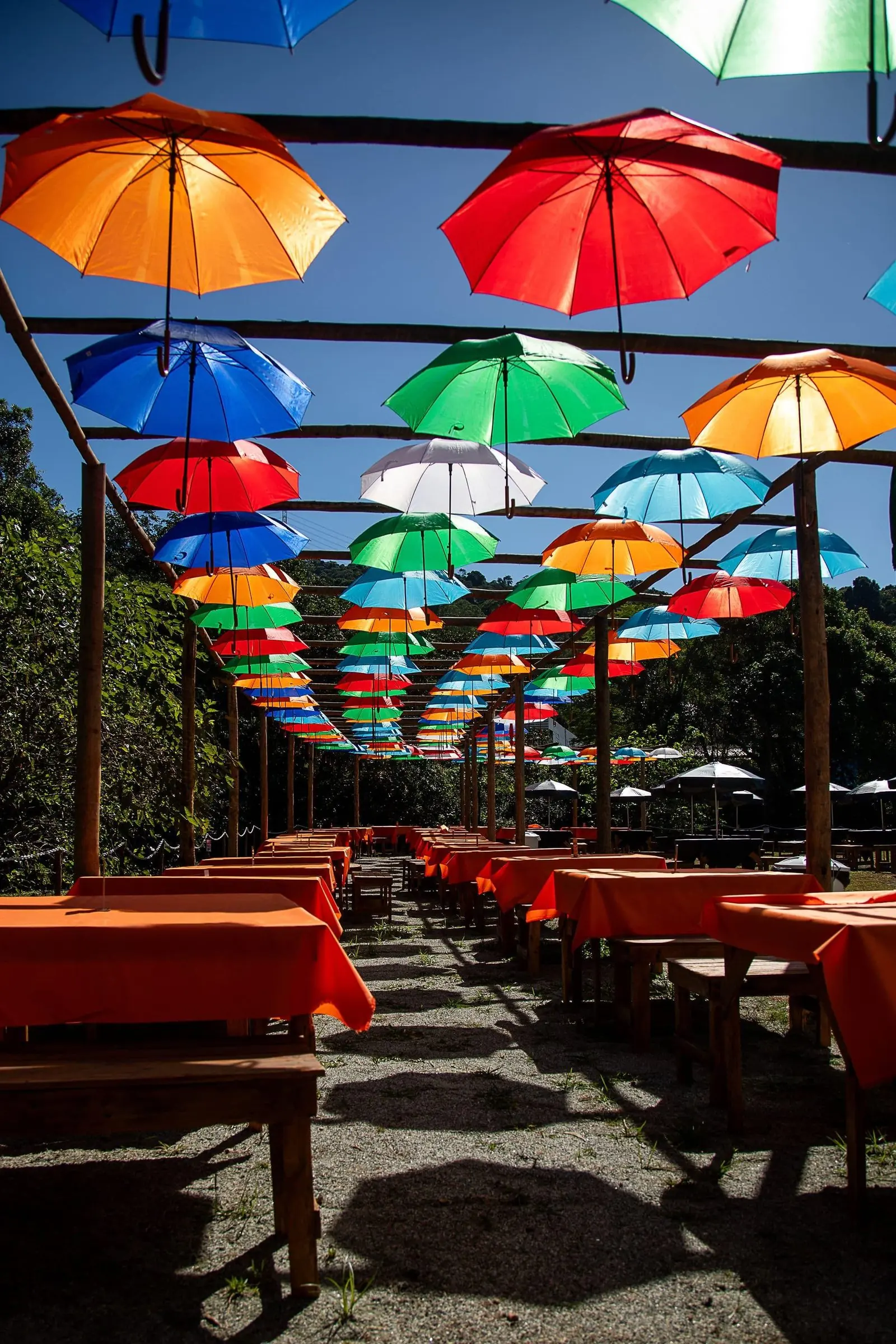 Mesas ao ar livre sob os guarda-chuvas coloridos no Rancho Santa Inês